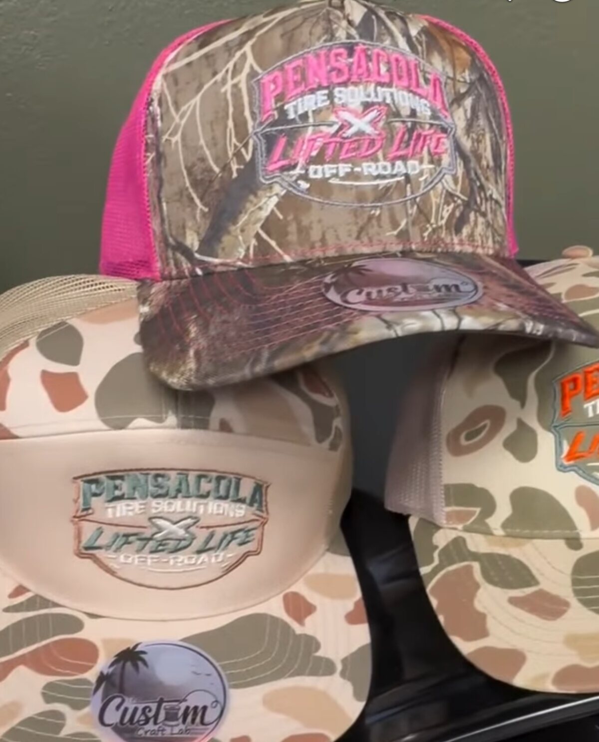 Camo trucker caps with pink and tan panels, embroidered for Pensacola Tire Solutions