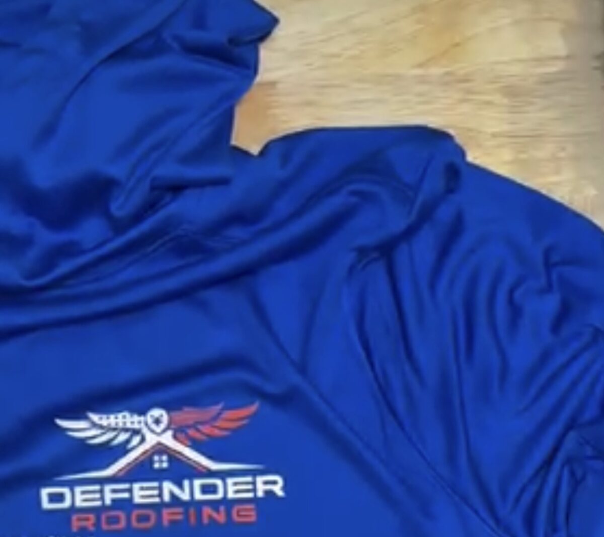 Royal blue performance hoodie embroidered with the Defender Roofing logo